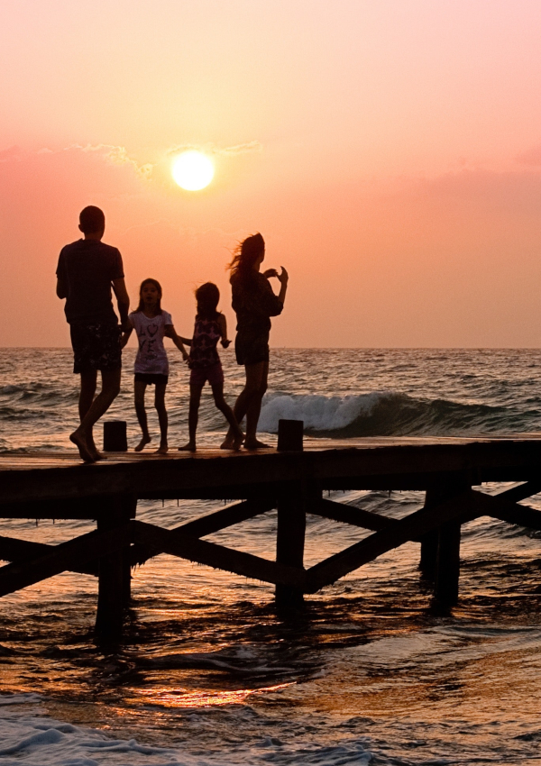 Stock photograph of a silhouette of a family on a pier in the sunset.